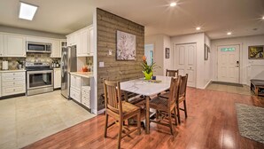 A modern kitchen with white cabinets, stainless steel appliances, and a wooden dining table with chairs. - Peaceful Forest Retreat by Mt. Baker Slopes! (Deming)
