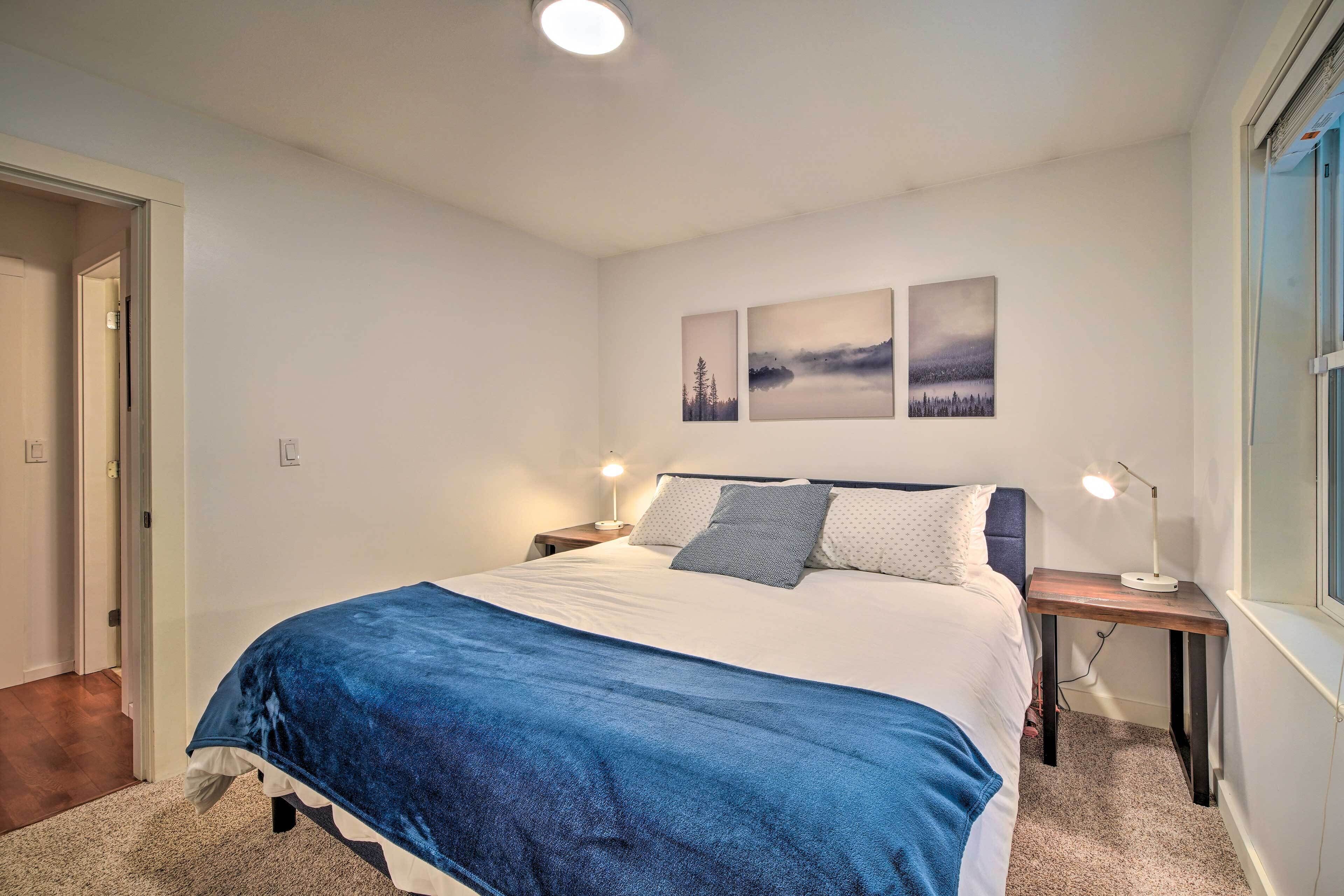 A bedroom with a bed, two bedside tables, and wall art.