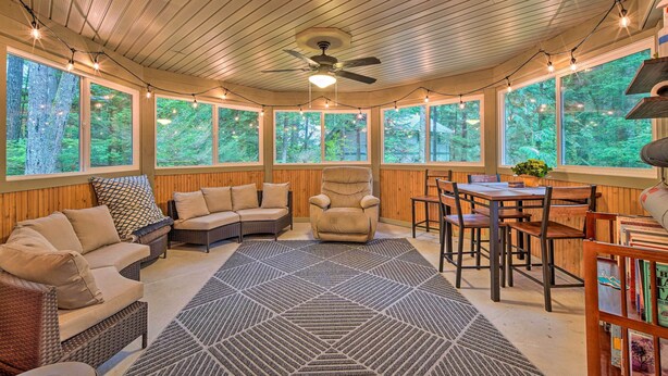 A sunroom with wooden walls, large windows, a ceiling fan, and a variety of seating including a sofa, chairs, and a table. - Peaceful Forest Retreat by Mt. Baker Slopes! (Deming)