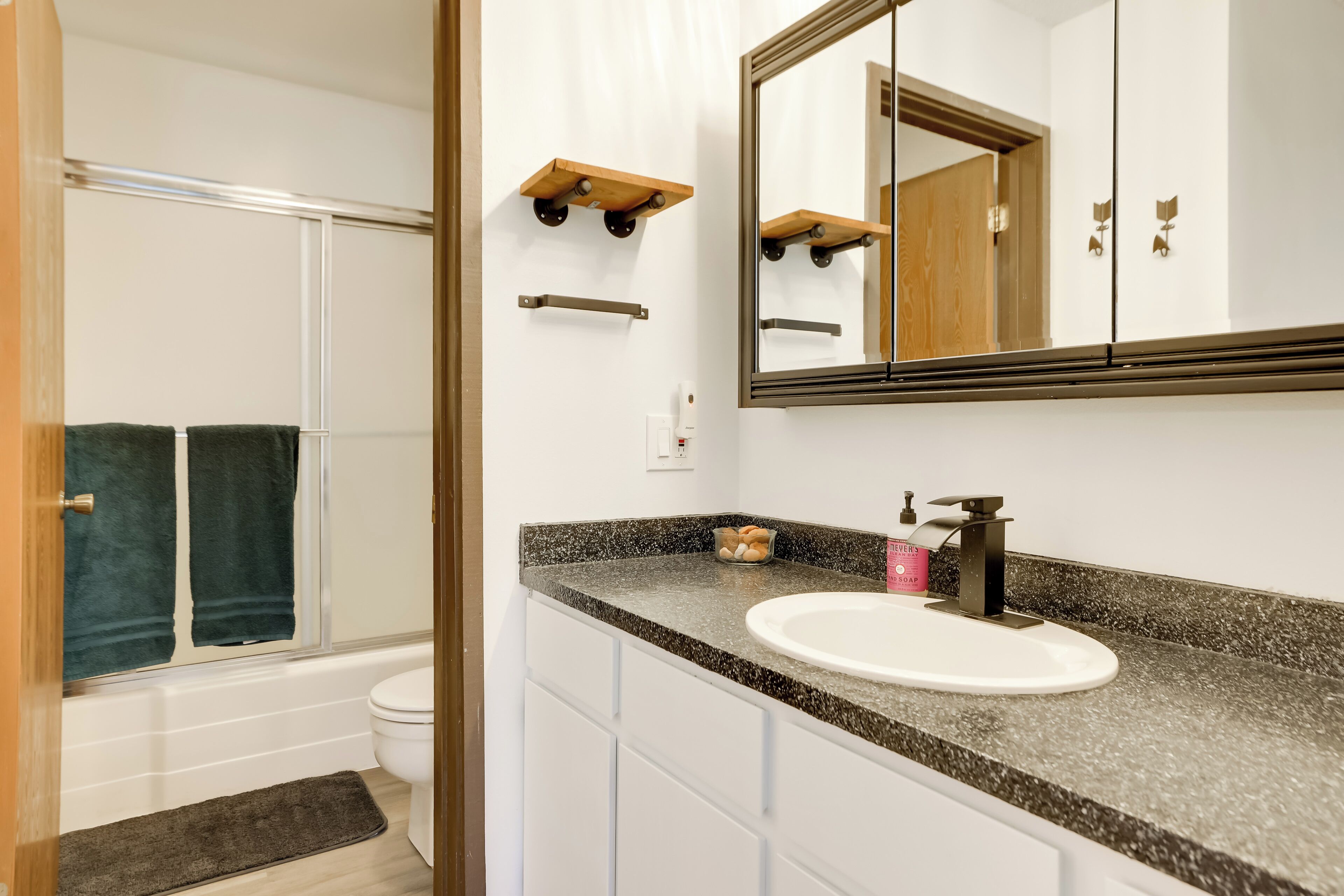 A bathroom with a white sink, a large mirror, and a shower area.