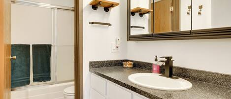 A bathroom with a white sink, a large mirror, and a shower area.