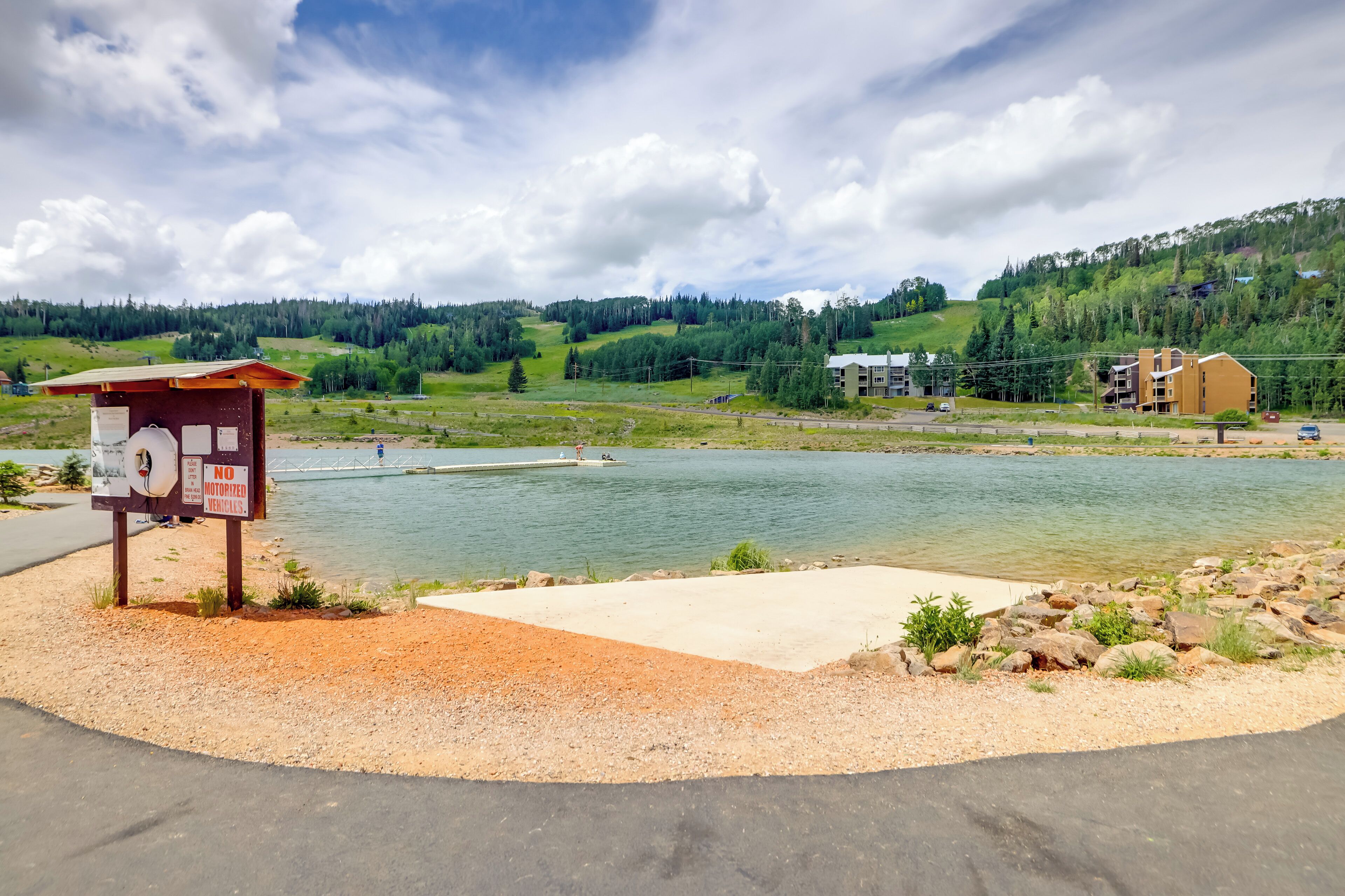 Une vue sur le lac, avec une plateforme d’observation en béton, un panneau indicateur et un bâtiment en arrière-plan.
