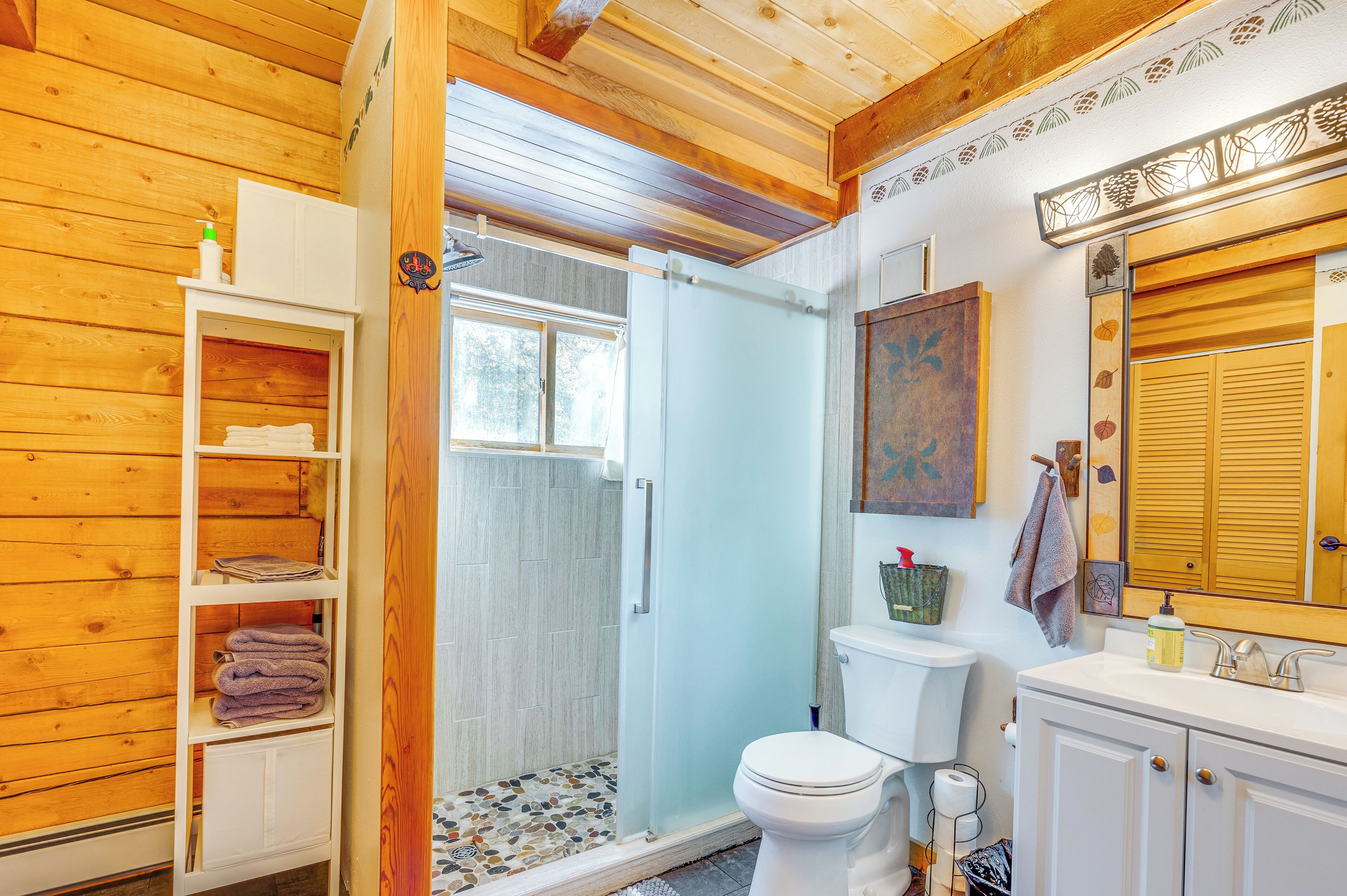 A wooden interior with a white toilet, a shower area, and a white cabinet with towels.