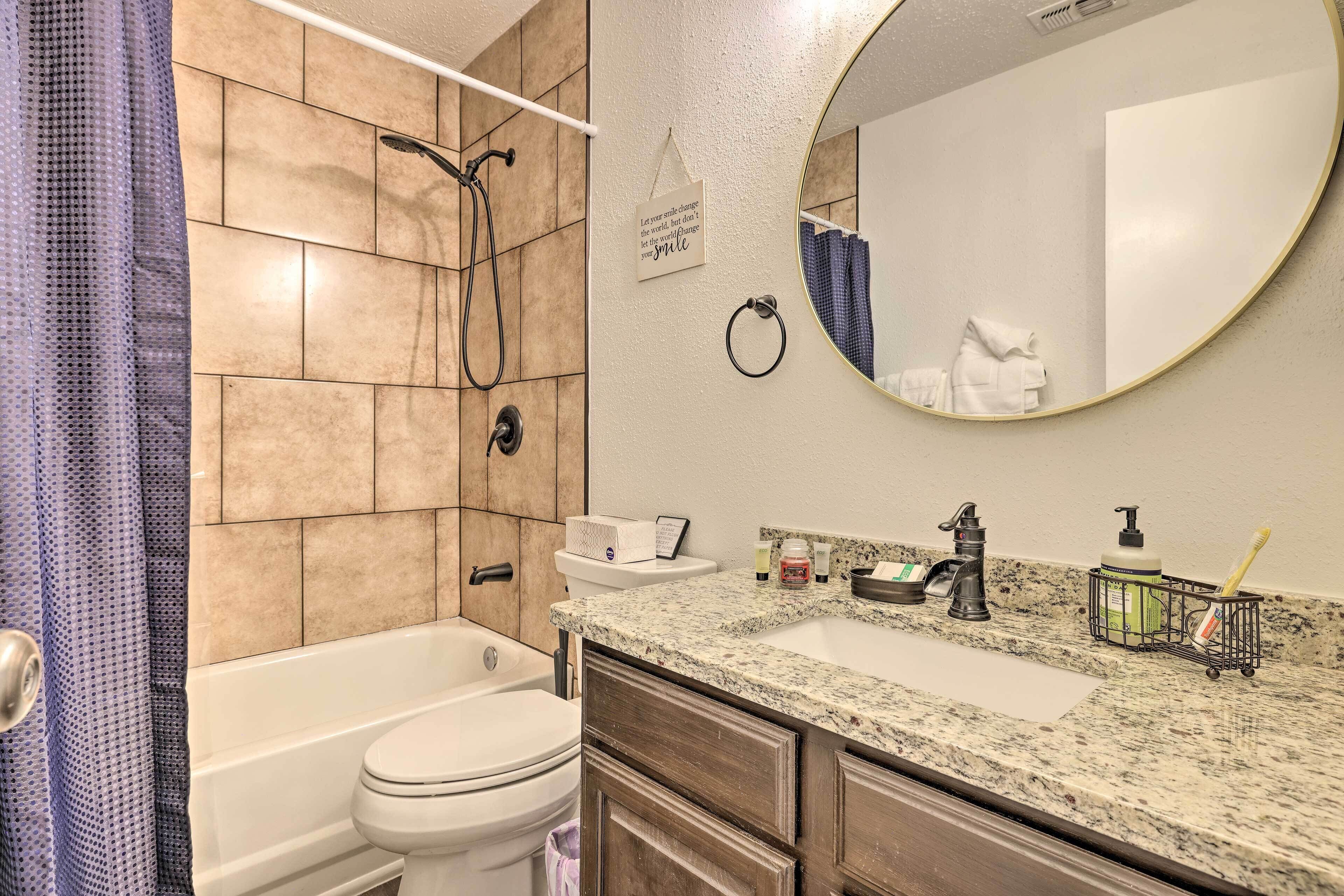A bathroom with a bathtub, toilet, sink, and a mirror.