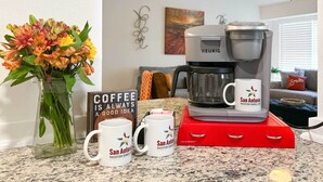 A kitchen with a coffee maker, two coffee mugs, and a vase of flowers. - San Antonio Family Home w/ Game Room & Fire Pit! (San Antonio)