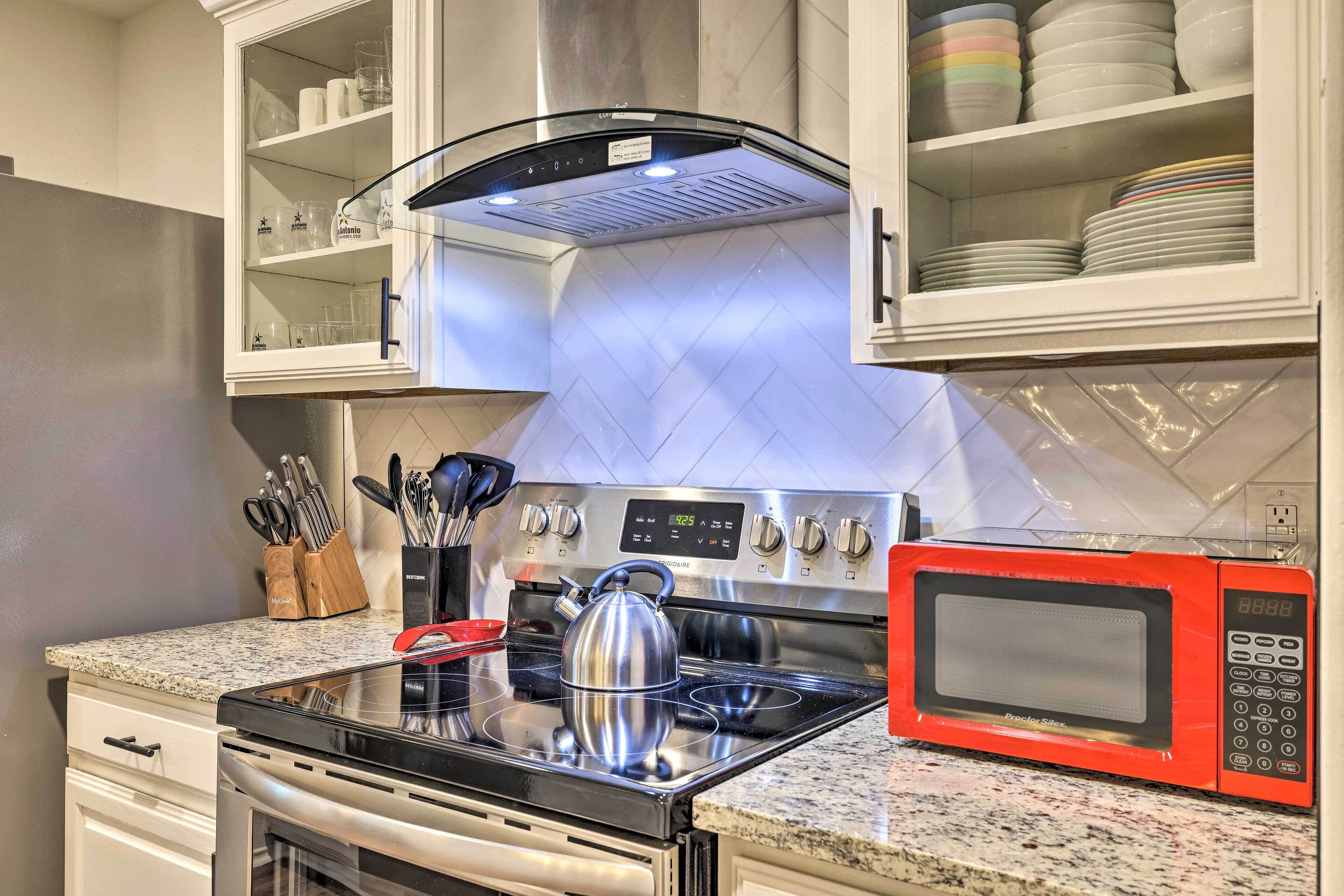 A modern kitchen with stainless steel appliances, a granite countertop, and a microwave.