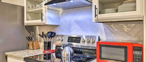 A modern kitchen with stainless steel appliances, a granite countertop, and a microwave.