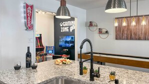 A kitchen with granite countertops, a stainless steel sink, pendant lighting, and a gaming zone sign. - San Antonio Family Home w/ Game Room & Fire Pit! (San Antonio)