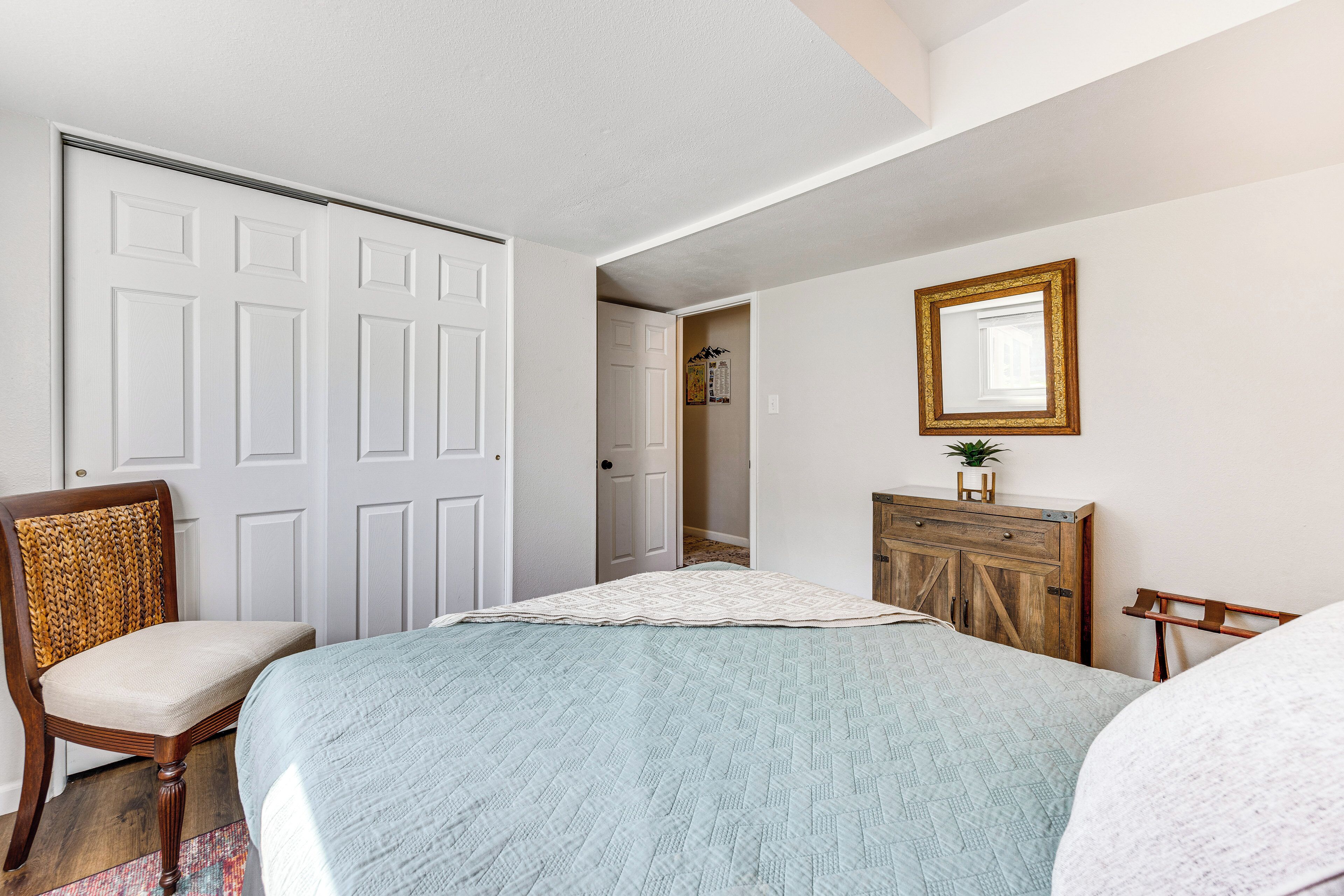 A bedroom with a bed, a chair, a dresser, and a mirror on the wall.