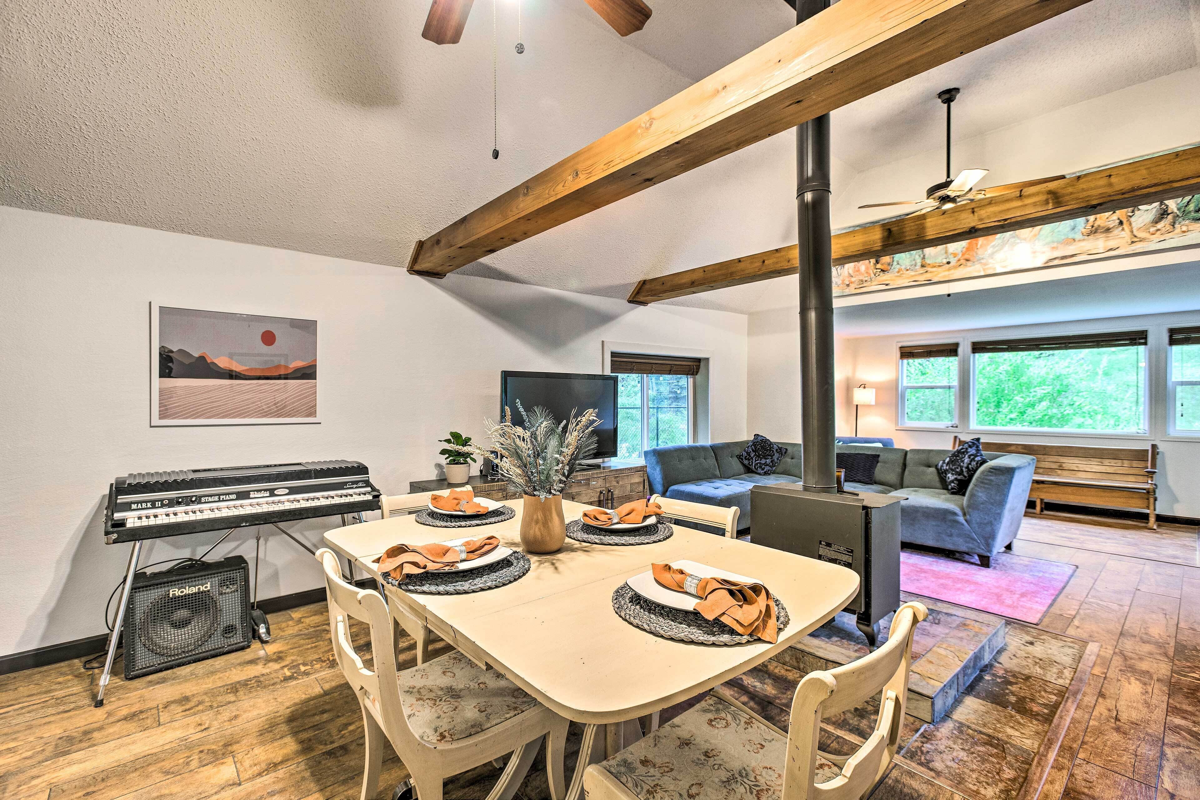 A dining area with a table set for four, a piano, and a television in the background.