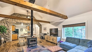 A cozy living room with a stone archway, a fireplace, a sofa, and a television. - Creekside Morrison Cabin ~ 9 Mi to Red Rocks Park! (Morrison)