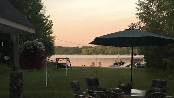 Une terrasse extérieure avec une table et des chaises, donnant sur un lac.