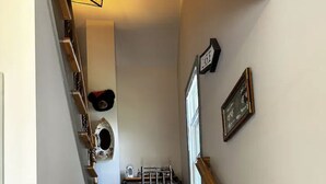 Un escalier avec des marches en bois et une rampe, menant à un palier où se trouvent une chaise et une petite table.