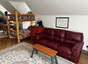 A cozy room with a bunk bed, a red sofa, a small table, and a patterned rug. - Cottage on Munro Lake (Levering)