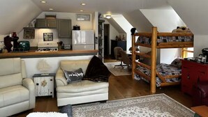 Une pièce de style loft comprenant une cuisine, un lit superposé, un canapé et un ventilateur de plafond.