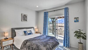 A bedroom with a bed, nightstands, a potted plant, and a view through a glass door. - Charming Buena Vista Home w/ Private Hot Tub! (Buena Vista)