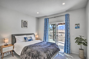 A bedroom with a bed, nightstands, a potted plant, and a view through a glass door. - Charming Buena Vista Home w/ Private Hot Tub! (Buena Vista)