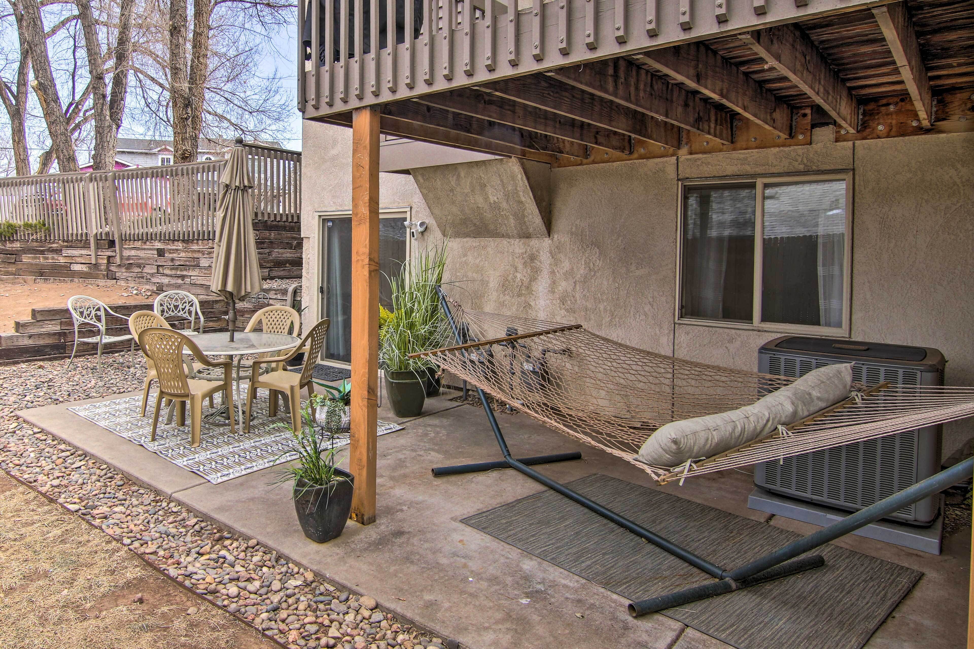 Une terrasse avec un ensemble de mobilier de jardin, un hamac et un grand climatiseur.
