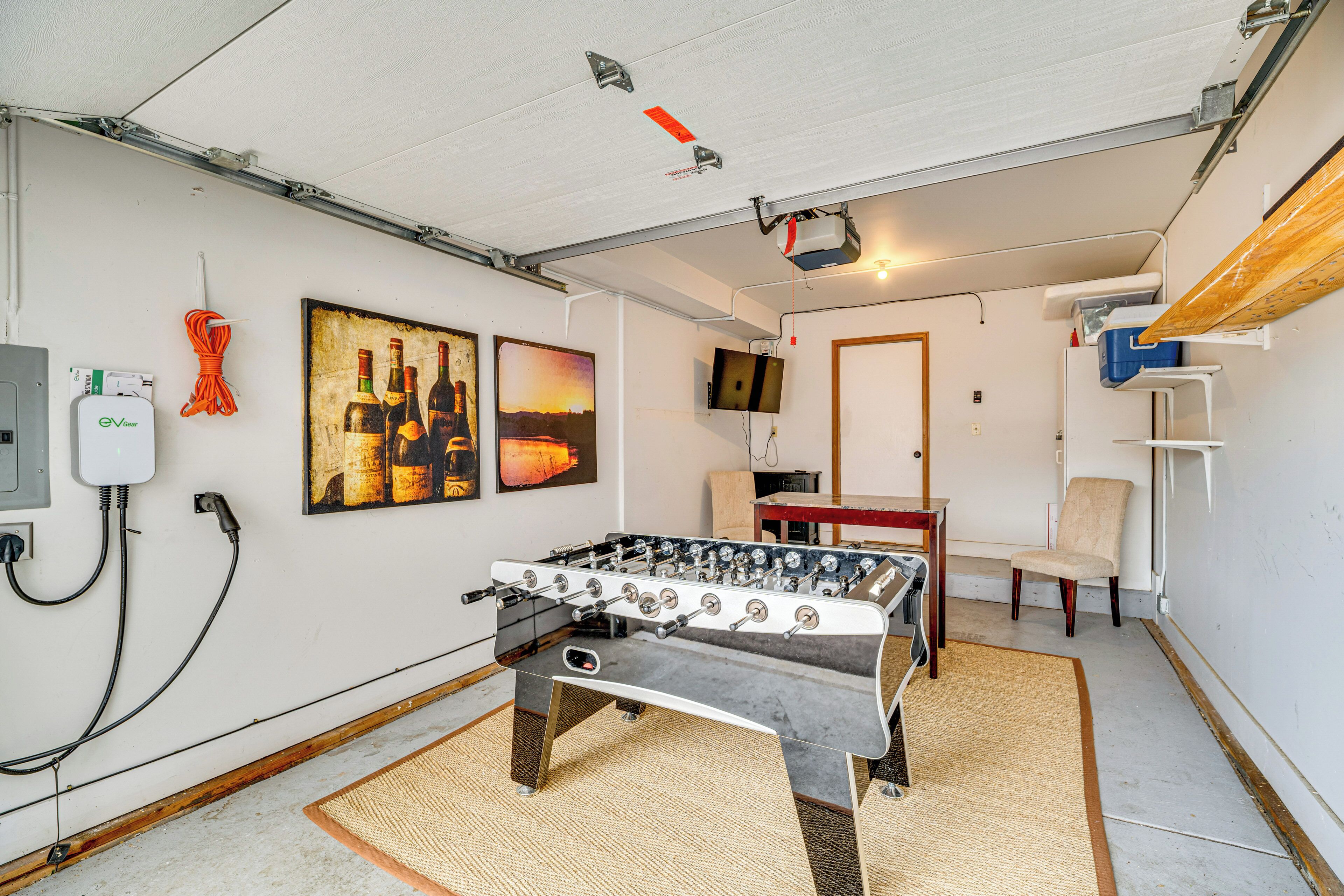 Una habitación con mesa de futbolín, televisión y obras de arte en la pared.