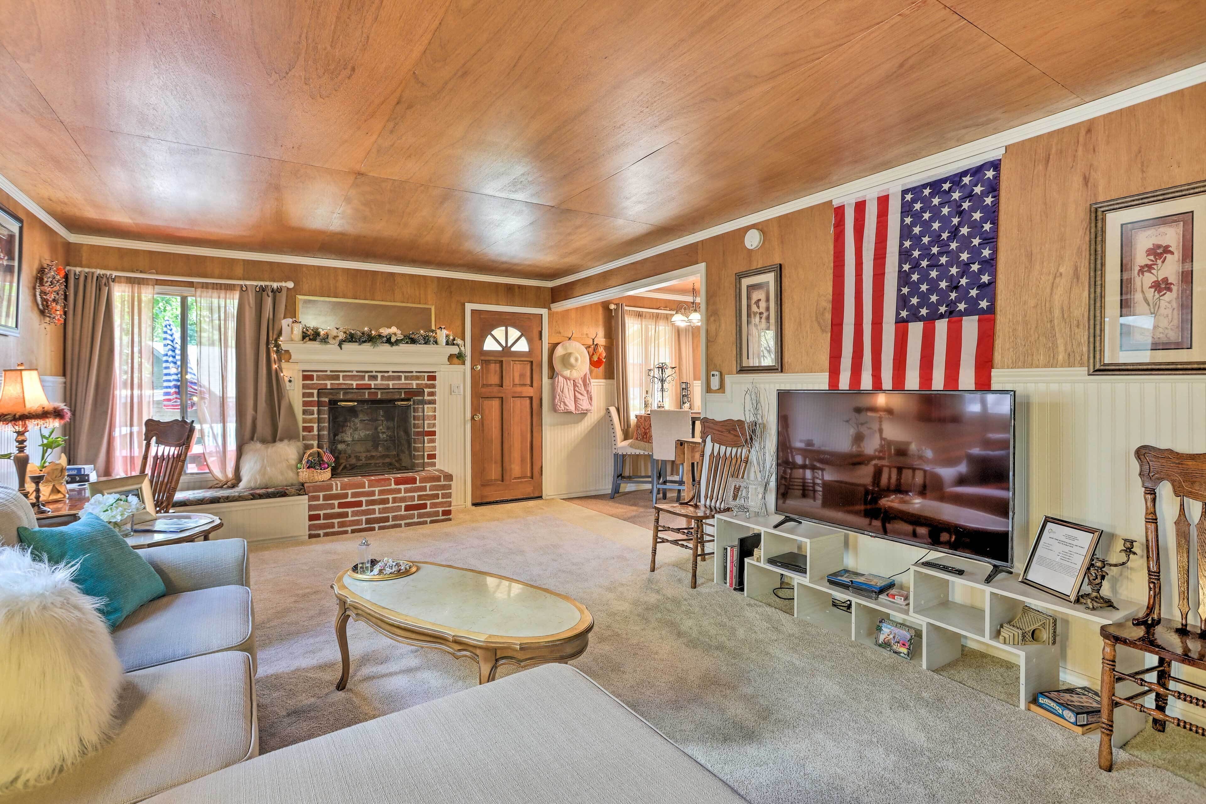 A cozy living room with a fireplace, a large American flag, and a television.
