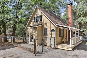A small, single-story house with a porch, a chimney, and a fenced yard.