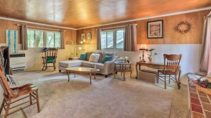 A spacious living room with a sectional sofa, a coffee table, and a fireplace. There are two windows with curtains, a wooden ceiling, and a wall-mounted wreath. - Cozy Crestline Cabin, Close to Lakes, Parks! (Crestline)