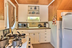 Una cocina con armarios blancos, estufa, microondas y refrigerador.