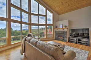 A spacious living room with a large window, a fireplace, and a leather sofa. - Idyllic Retreat ~ 20 Mi to Olympic National Park! (Port Angeles)