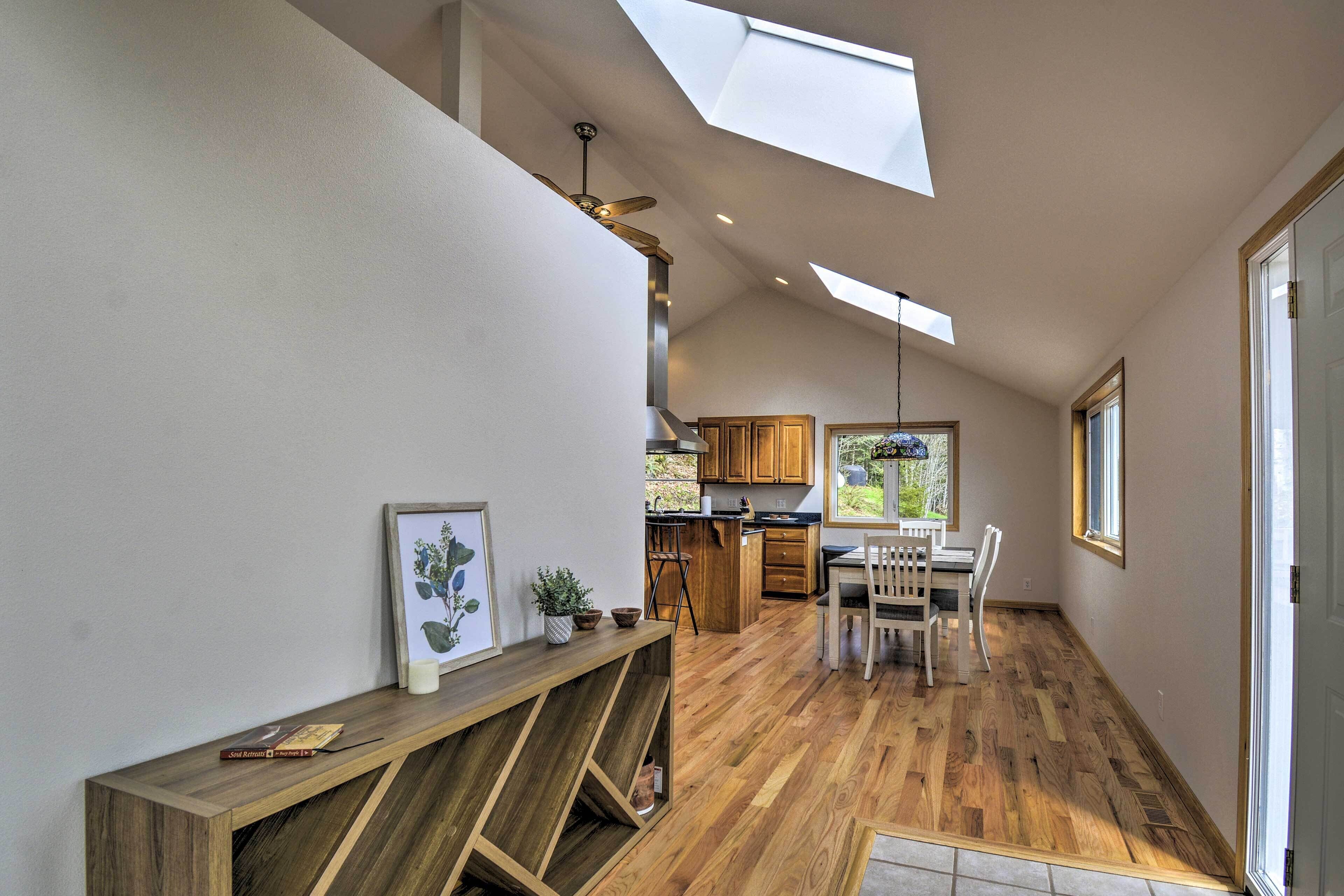 A spacious kitchen with wooden cabinets, a dining area with chairs, and a skylight.