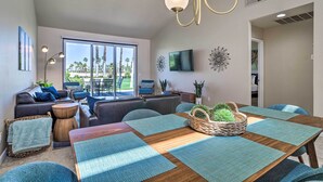 Una sala de estar moderna con un ventanal grande, un comedor con mesa de madera y un conjunto de sofás y sillones.