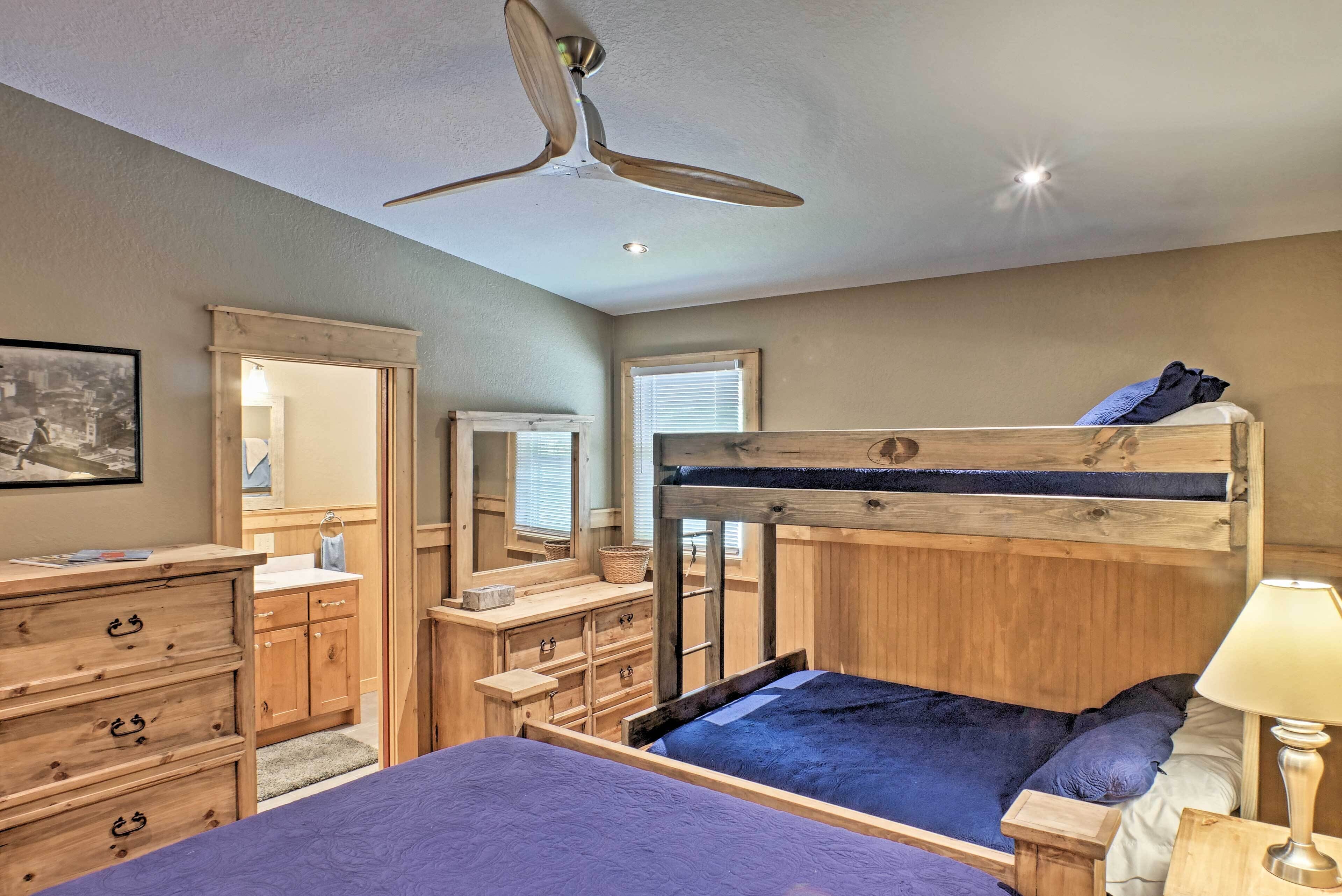 Une chambre avec un lit superposé, une commode en bois, un miroir et un ventilateur de plafond.