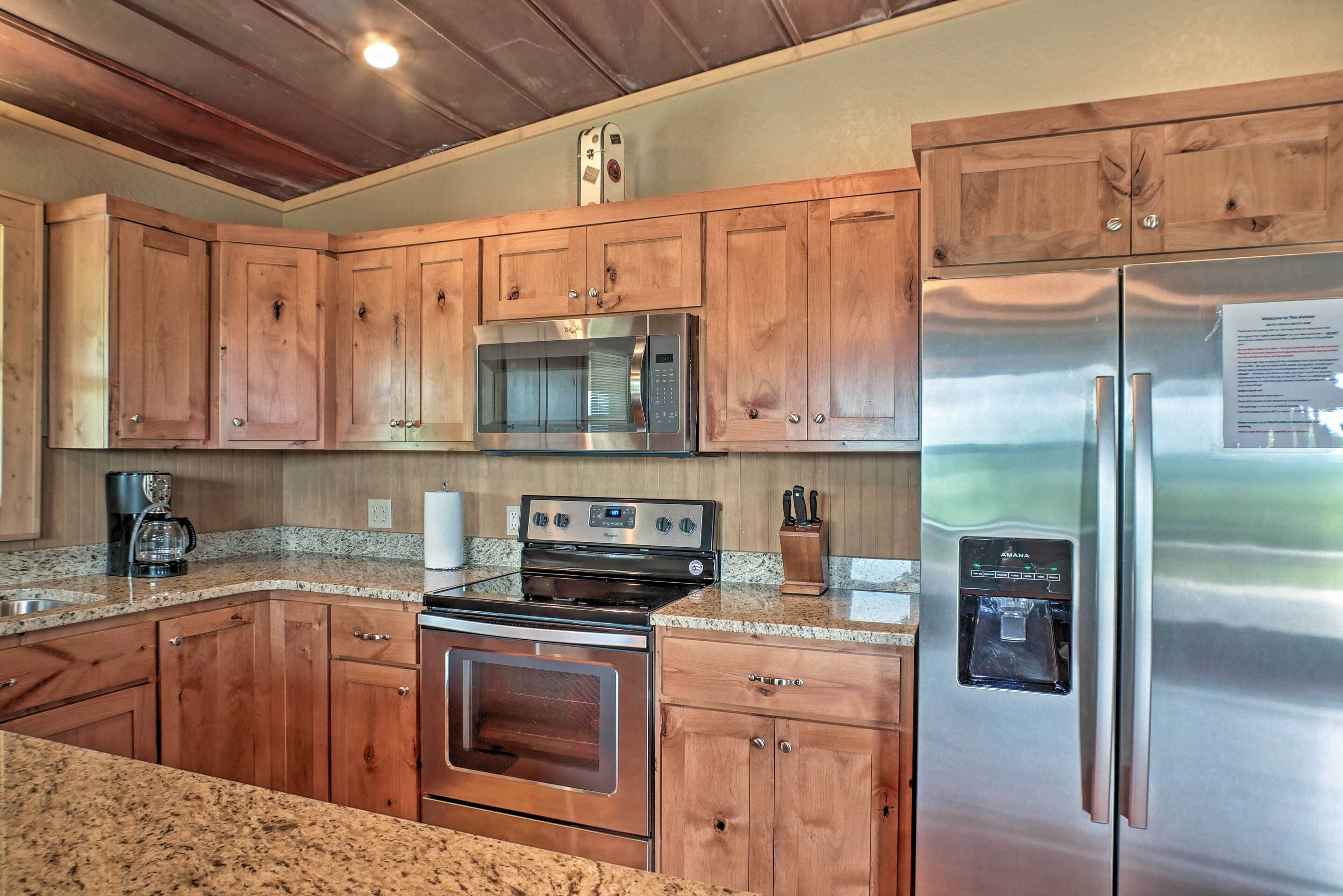 A kitchen with wooden cabinets, stainless steel appliances, granite countertops, and a built-in water dispenser.