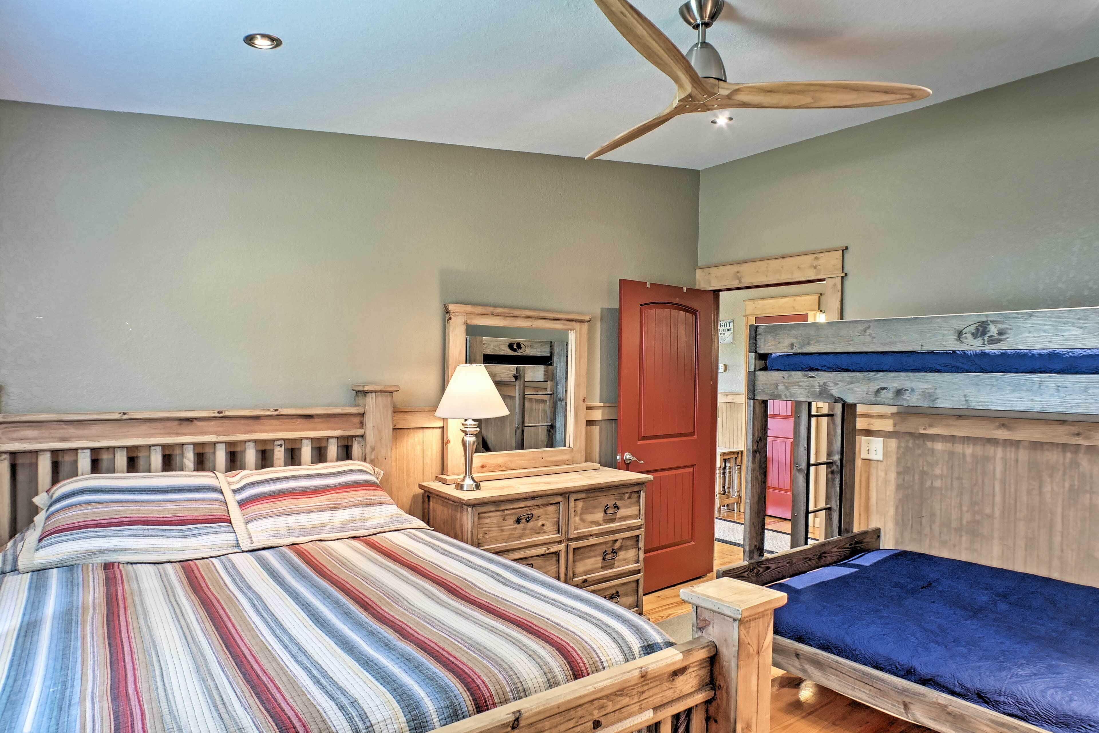 A bedroom with a bunk bed, a wooden dresser, a mirror, and a ceiling fan.
