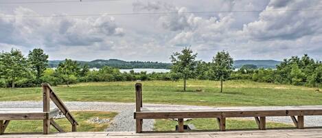 A wooden deck with benches overlooking a grassy area and a body of water.