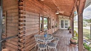 A wooden porch with a round table and chairs, a ceiling fan, and potted plants. - 40-acre Farm w/ Animals & Fishing in Sebring! (Sebring)