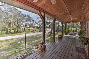 A covered outdoor patio with wooden flooring, potted plants, and a table and chairs. - 40-acre Farm w/ Animals & Fishing in Sebring! (Sebring)