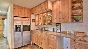 A kitchen with wooden cabinets, a stainless steel refrigerator, and a granite countertop. - 40-acre Farm w/ Animals & Fishing in Sebring! (Sebring)
