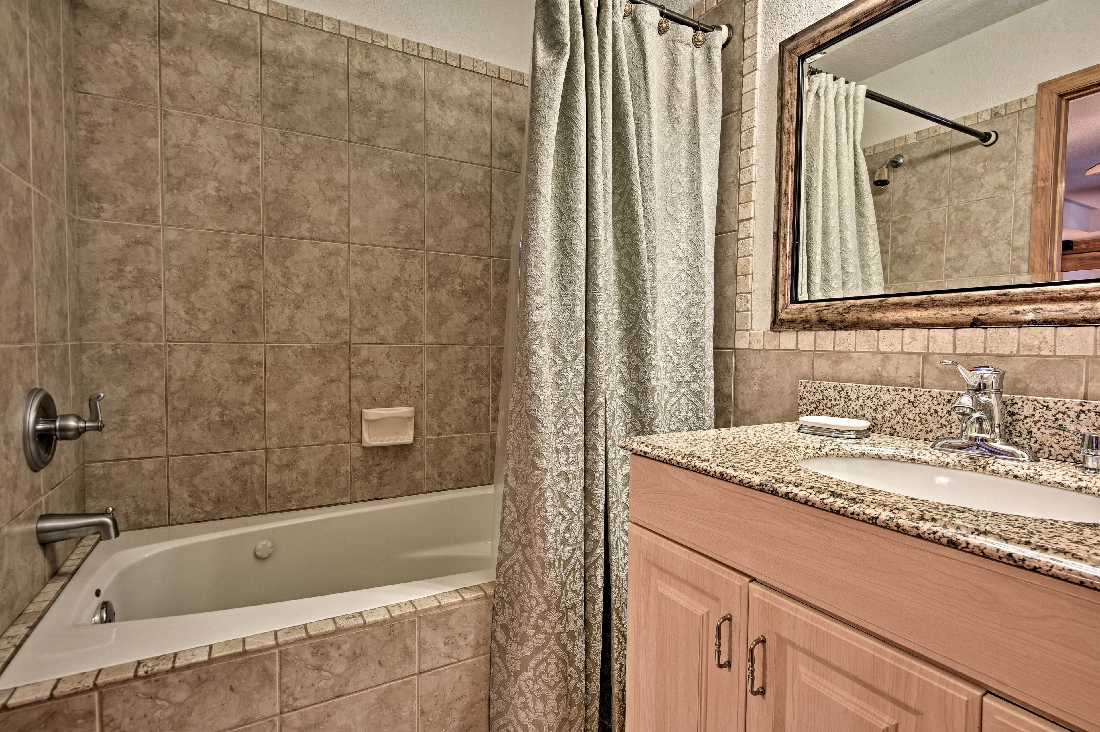 A bathroom with a bathtub, a sink, and a mirror.
