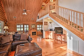 A spacious living room with a large brown leather sofa, a fireplace, and a wooden staircase. - Rustic 4BR Farm Retreat Near Sebring Raceway (Sebring)