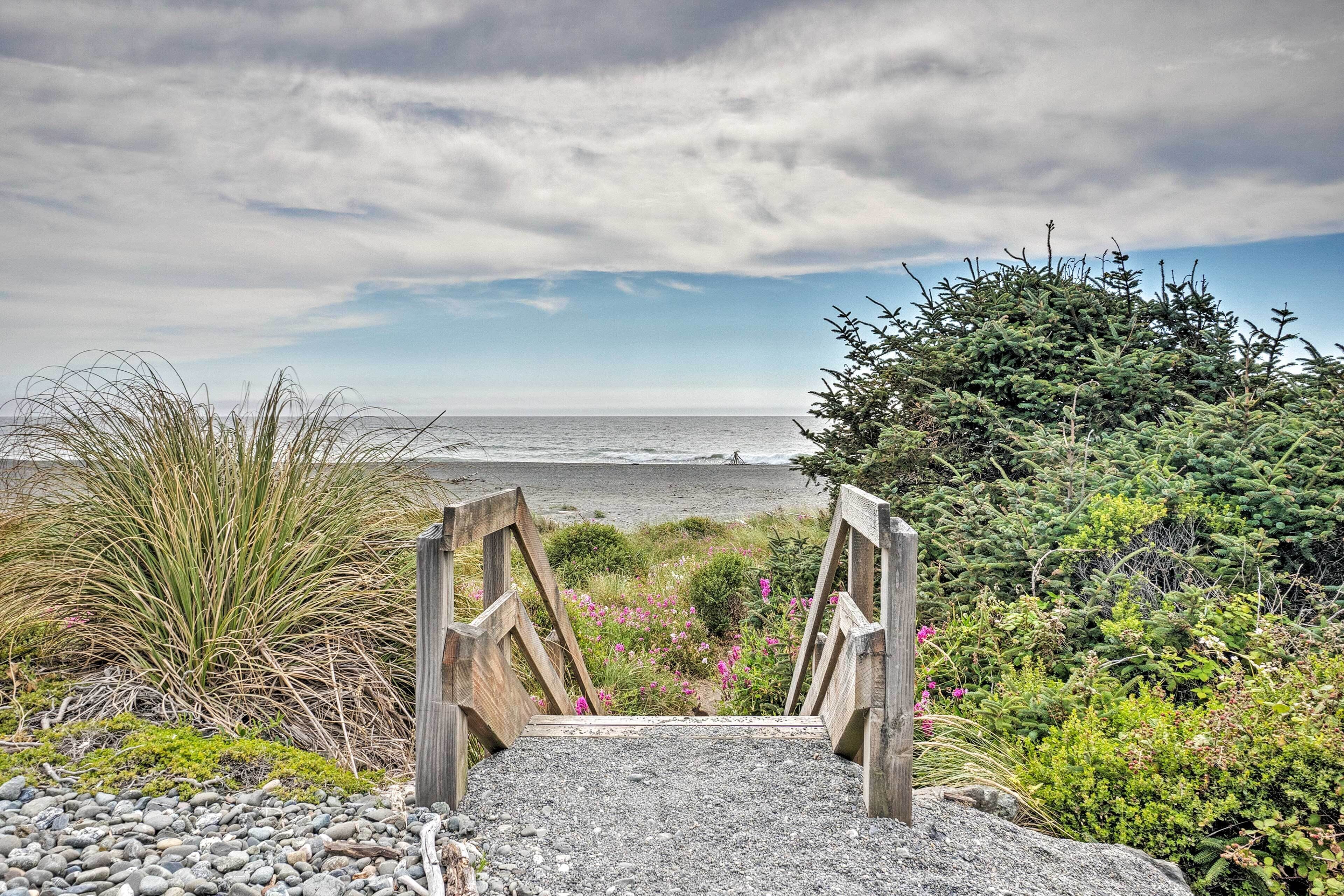 A wooden pathway leading to a beach with a view of the ocean.