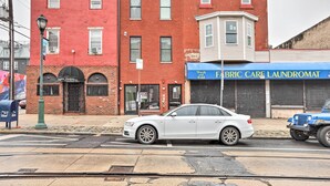 A street view with a red brick building, a white car, and a blue truck. - Classy Philly Apartment: 2 Mi to Downtown! (Philadelphia)