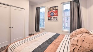 A bedroom with a bed, a window with curtains, a wall with a poster, and a door. - Classy Philly Apartment: 2 Mi to Downtown! (Philadelphia)