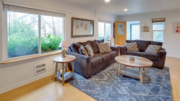 Ein modernes Wohnzimmer mit einem braunen Sofa, zwei Beistelltischen und einem blauen Teppich mit Muster.