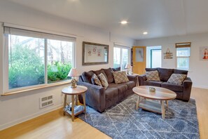 A modern living room with a brown sofa, two side tables, and a blue patterned rug. - Charming Gold Beach Home < 1 Mi to Rogue River! (Gold Beach)