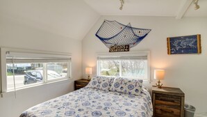 Ein Schlafzimmer mit einem an das maritime Thema angelehnten Bettbezug, einer Wanddekoration mit einer Karte und einem Schild mit der Aufschrift "CAPTAIN'S QUARTERS".