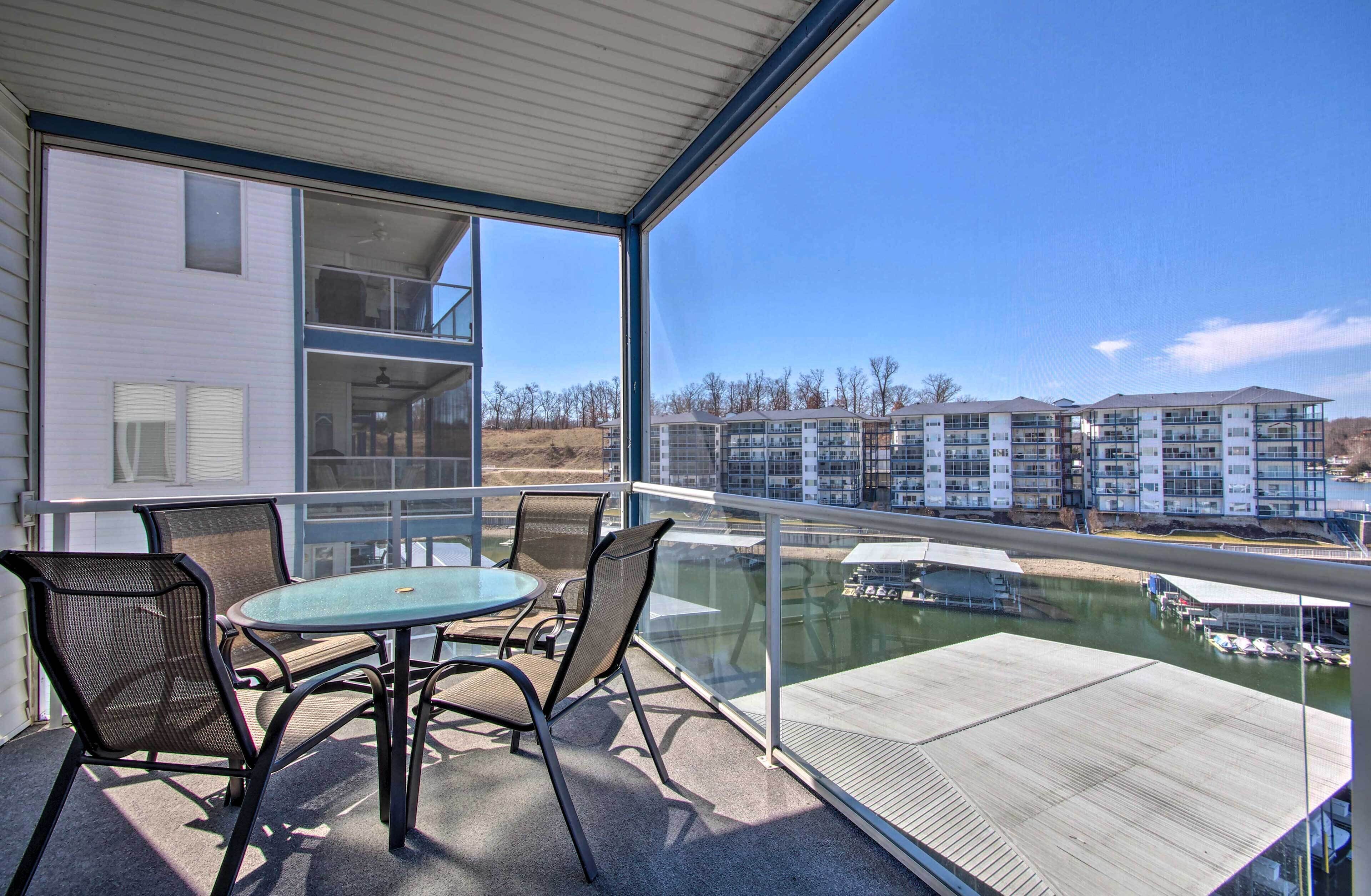 A balcony with a glass railing, a table, and four chairs.