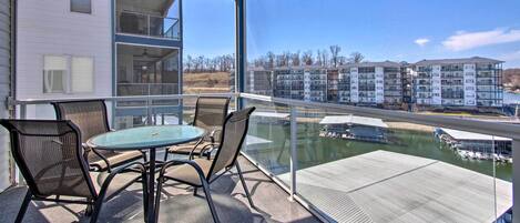 A balcony with a glass railing, a table, and four chairs.