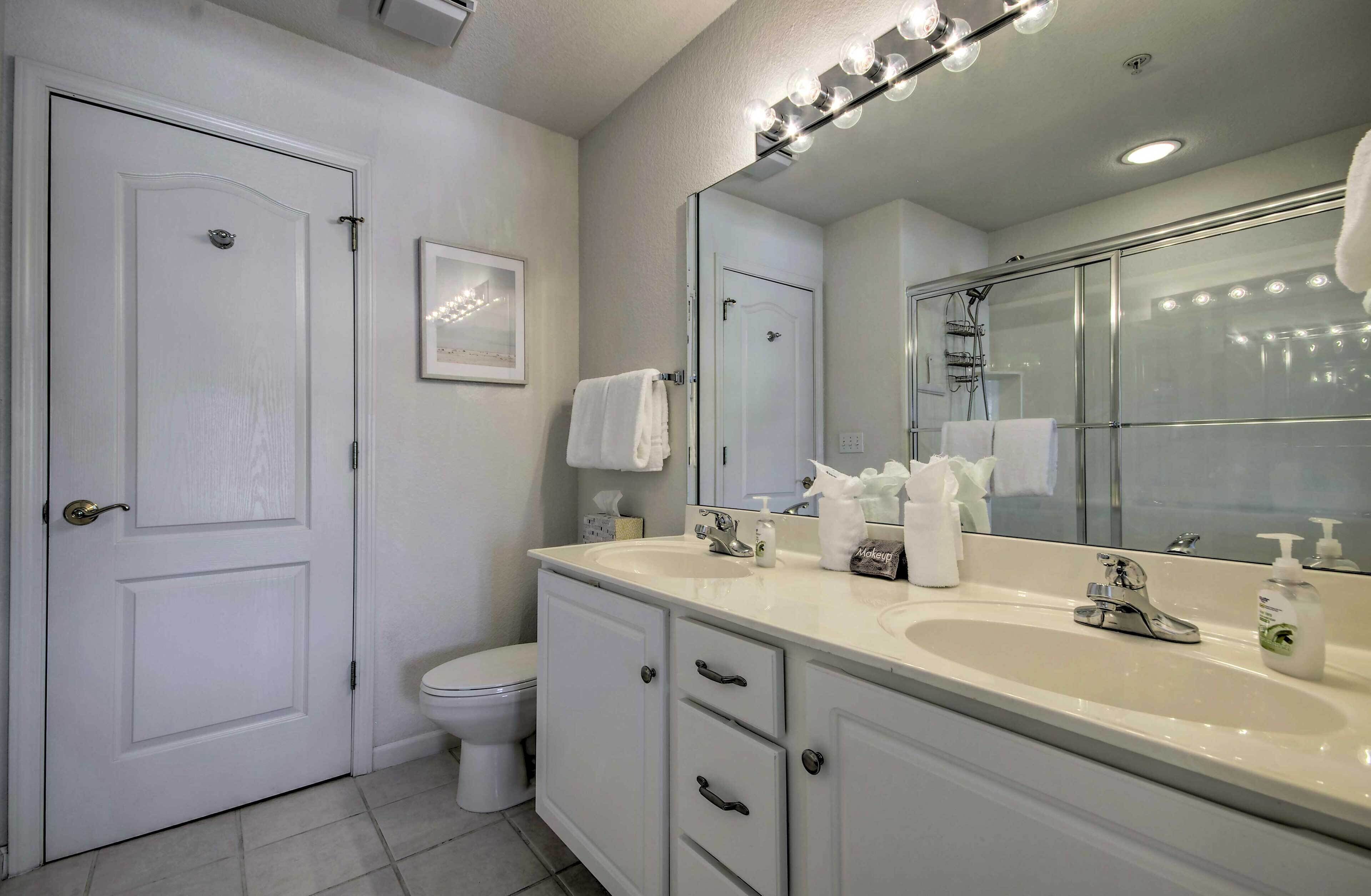 Une salle de bain avec un meuble-lavabo blanc, un grand miroir et un espace douche.