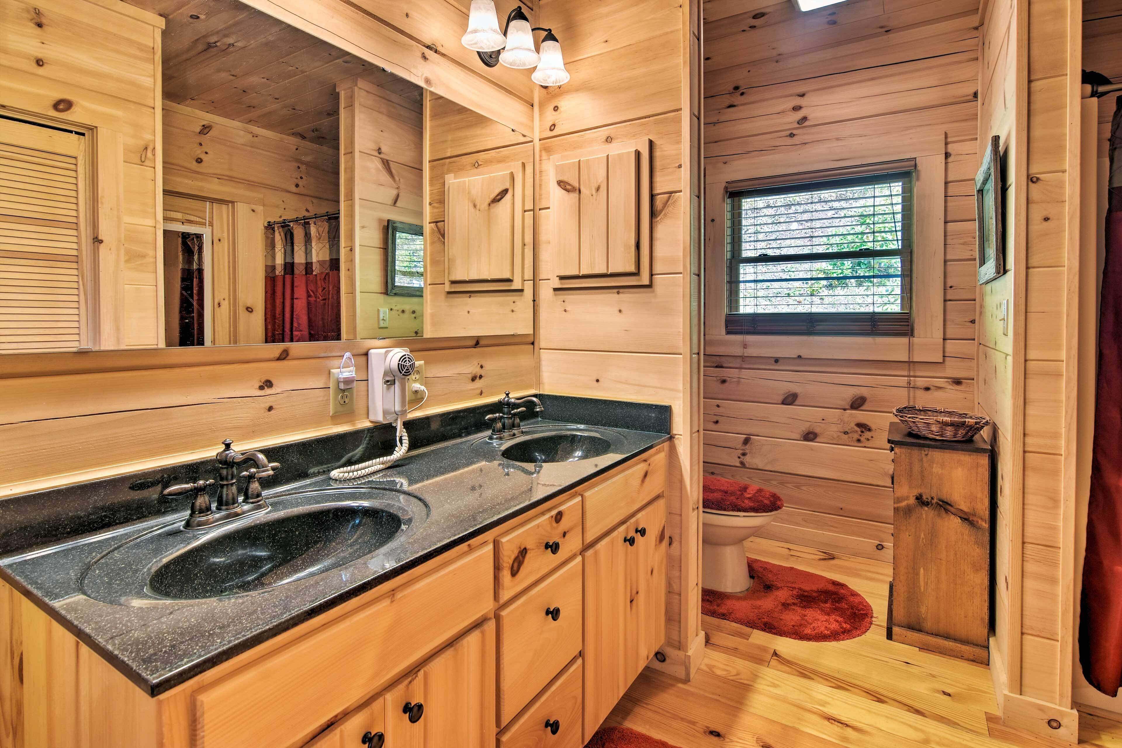 Baño de cabaña de madera con dos lavamanos, un espejo grande y una ventana.