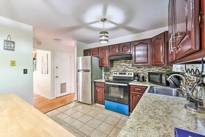 A modern kitchen with stainless steel appliances, dark wooden cabinets, and a granite countertop. - Deck & Backyard: Tobyhanna Family Home (Tobyhanna)